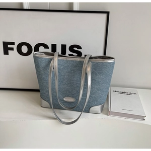 Detail of blue denim tote bag with silver metallic trim and stylish contrast stitching