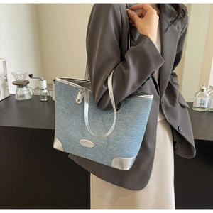 Close-up of light blue denim tote bag featuring shiny silver metallic trim and handles