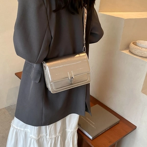 Metallic silver square crossbody bag with bohemian strap shown from a side perspective