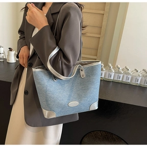 Detail of blue denim tote bag with silver leather trim and metallic finish accents
