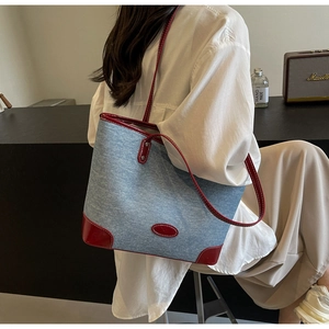 Detail of blue denim tote bag with red leather trim and shoulder strap in retro style