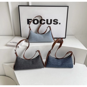 Three denim hobo bags in light blue, dark gray and navy with brown leather straps