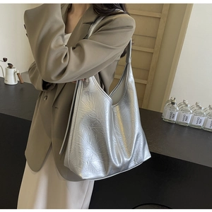 Close-up of silver tote bag with metallic crinkle texture and wide shoulder strap
