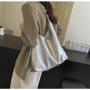 Detail of silver metallic tote bag with crinkled texture worn on model's shoulder
