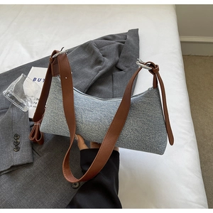 Detail of blue denim hobo bag with brown leather strap and silver metal zipper closure