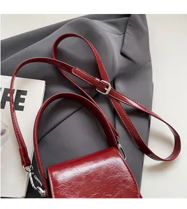 Détail du sac à bandoulière en cuir rouge brillant avec sangle réglable et boucle en métal