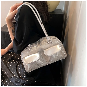 Detail view of metallic silver boston bag with dual front pockets on model's shoulder
