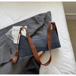 Detail of blue denim shoulder bag with brown leather strap and silver metal rings