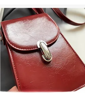 Détail de la texture en cuir ciré rouge foncé et du fermoir en métal argenté du sac