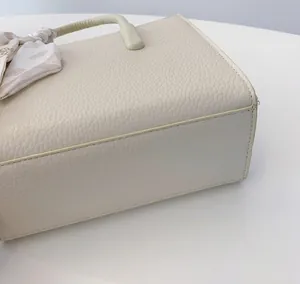 Detailansicht der cremefarbenen Ledertasche mit Litchi-Struktur und feinen Nähten