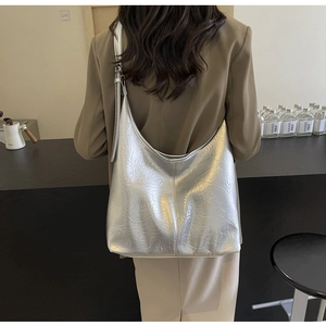 Close-up of metallic silver hobo bag with pleated texture worn on model's shoulder