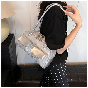 Close-up of silver metallic shoulder bag with crackle texture and front pockets on model