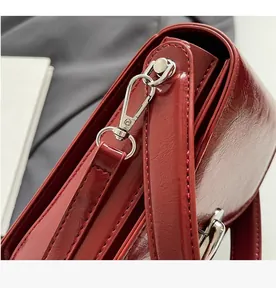 Détail de cuir rouge brillant avec crochet en argent et anneau en D sur le mini sac