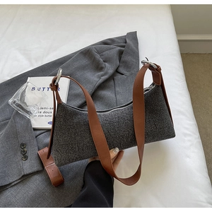 Detailed texture of dark grey wool fabric baguette bag with elegant brown leather strap