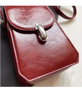 Détail de la texture en cuir verni rouge et boucle en métal argenté du sac portable