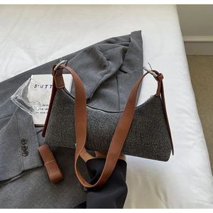 Close-up of gray tweed fabric and brown leather strap on minimalist shoulder bag