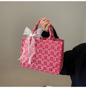 Detail der Stickerei mit chinesischem Xi-Symbol auf roter Tasche mit weißer Schleife