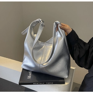 Close-up of metallic silver tote bag featuring pleated texture and adjustable buckle