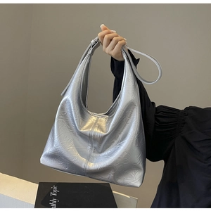 Close-up of silver metallic tote bag featuring pleated texture and adjustable strap