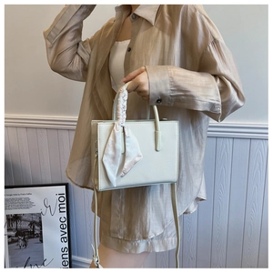 Detailansicht der weißen Tasche mit Litschi-Struktur und elegantem Seidenschal-Griff