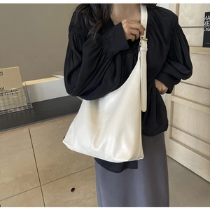 Detail of white leather hobo bag featuring soft pleats and adjustable gold buckle strap