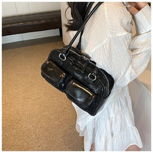 Model wearing a black glossy oil wax leather shoulder bag with silver hardware accents