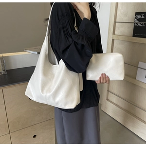 Detailed shot of white pleated leather tote bag with matching zippered pouch on a shoulder