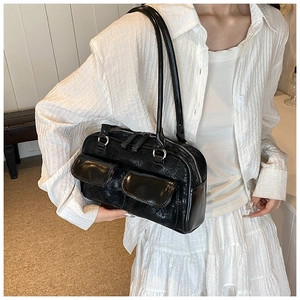 Detail of vintage black shiny leather shoulder bag with two front pockets and silver zippers