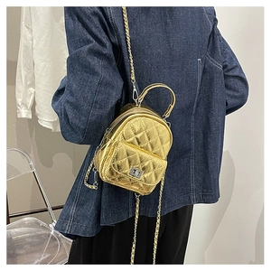 Detail of mini gold quilted backpack with chain strap and metal turn-lock on model