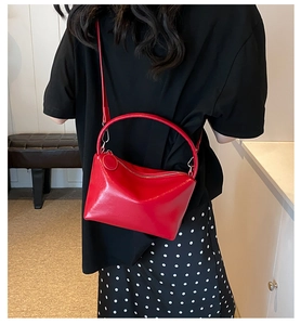 Red leather handbag with top handle and shoulder strap shown in lifestyle context