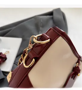 Detailed shot of burgundy and beige leather contrast bucket bag with gold hardware