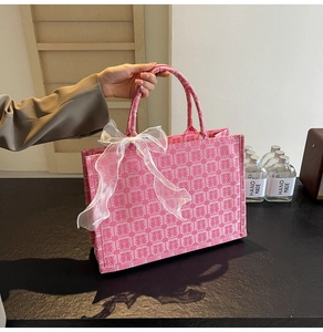 Nahaufnahme der rosa Jacquard-Tragetasche mit Xi-Muster und eleganter Organza-Schleife