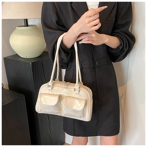 Detailed macro view of cream-colored glossy leather shoulder bag with flap pockets