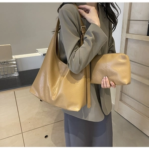 Detail of light brown PU leather tote bag with matching zippered pouch on a model