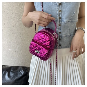 Detail of a mini quilted chain backpack in metallic magenta with silver twist lock closure