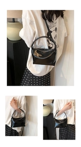 Detail of glossy black leather handbag with rounded handle and metallic zipper closure