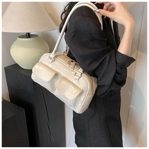 Detail of a creamy white glossy Boston shoulder bag with dual front pockets and silver hardware