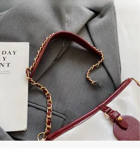 Detailed close-up of contrasting red and white chain bucket bag on grey suit fabric