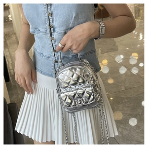 Detailed close-up of a silver quilted mini backpack with chain strap and twist lock