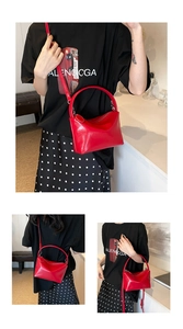 Detailed close-up of bright red minimalist small handbag with a unique curved handle and strap