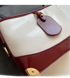 Detail of contrast stitching, burgundy leather trim and gold ring hardware on the bag