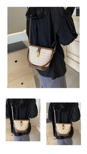 Detail of contrast woven straw bucket bag with brown leather trim and gold buckle