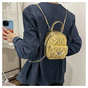 Detail of a gold metallic quilted mini backpack featuring chain straps and a twist lock