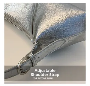 Detail of adjustable shoulder strap with silver metal buckle on silver wrinkled leather bag