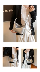 Detail of silver metallic handbag with circular hard handle and zip closure mechanism