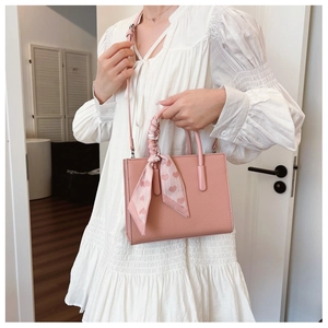 Detailansicht der rosa Ledertasche mit dekorativem Herzmuster-Schal am Tragegriff
