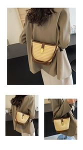 Detail of straw woven bucket bag with brown leather trim and golden metal clasp