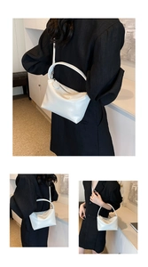 Close-up of a minimalist white trapezoid handbag with silver zipper and leather texture