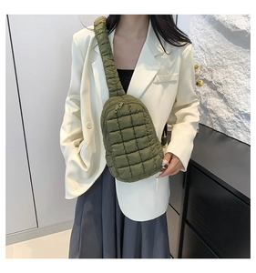 Army green quilted nylon crossbody bag with wide shoulder strap worn by a model