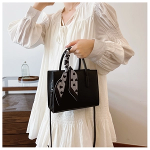 Detail der schwarzen Tote-Bag aus genarbtem Leder mit einem bedruckten Seidenschal-Griff